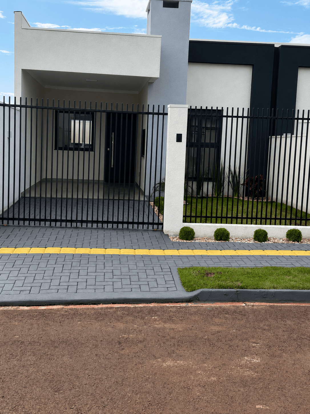 Frente da casa nova com portão e jardim