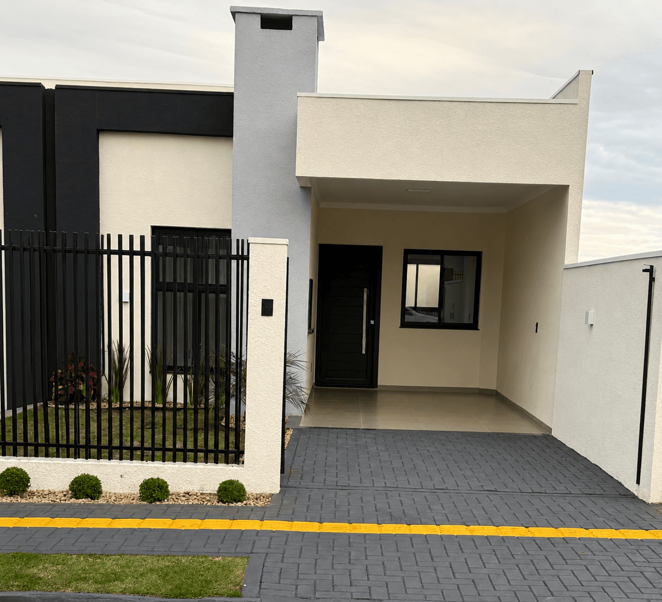 Entrada da casa com garagem coberta e jardim