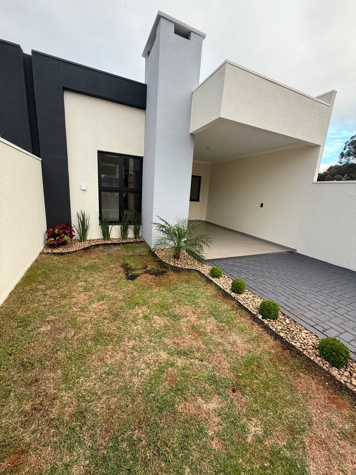Garagem coberta e jardim na frente da casa